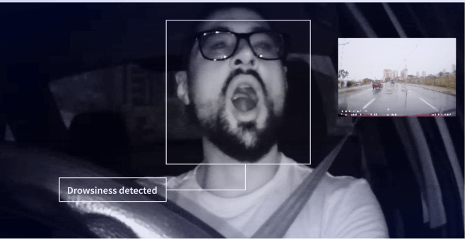 Person yawning while driving and camera detecting fatigue.