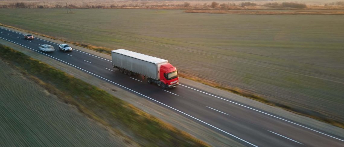 Vista aérea de um semi-caminhão desfocado em movimento rápido com reboque de carga dirigindo na rodovia