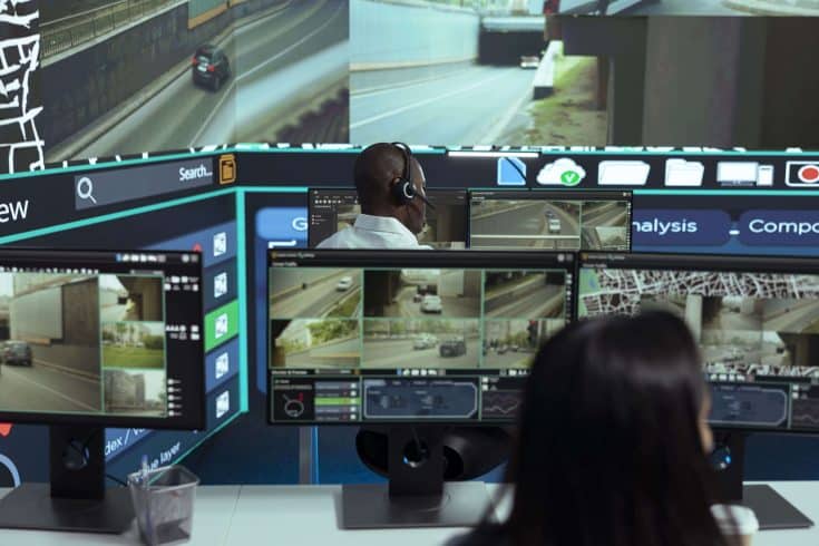 Central de monitoramento com profissionais acompanhando imagens de câmeras de segurança de veículos.