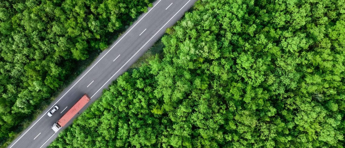 Vista aérea superior de carro e caminhão dirigindo na estrada na floresta verde.