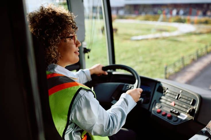 Motorista profissional conduzindo veículo de transporte com colete de segurança, representando boas práticas de segurança viária e gestão de riscos jurídicos da frota.