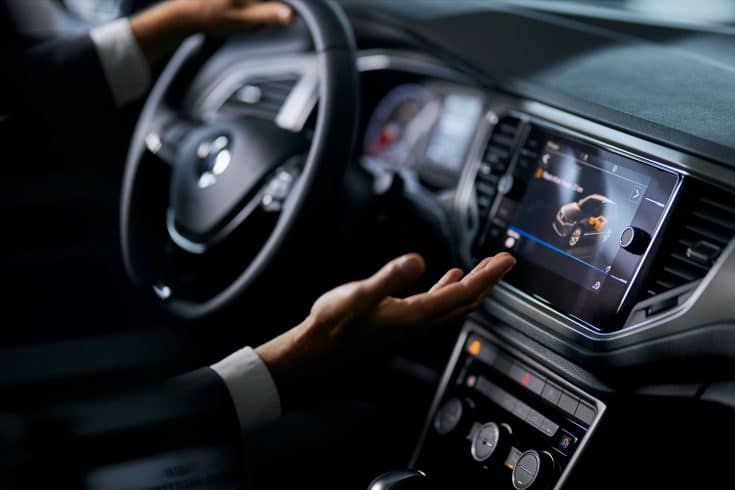 Painel de carro iluminado durante a condução noturna, com sistema de navegação ativo e motorista ao volante, ilustrando a conectividade da tecnologia Over the Air na frota.