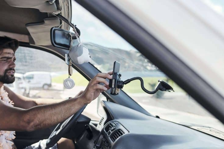 Motorista ajusta celular no painel do veículo, representando o uso de tecnologia para saber se o sistema de gestão de frota entrega.