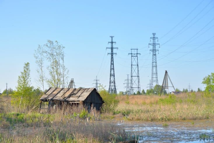 Área rural com torres de transmissão de energia ao fundo e vegetação ao redor, ilustrando a faixa de servidão e sua convivência com o uso do solo e o ambiente natural.