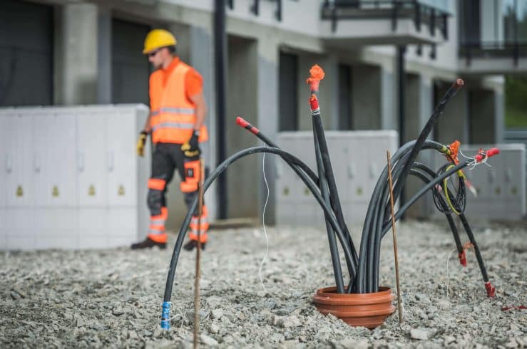 Cabos expostos em obra evidenciam risco de furto de cabos, com técnico ao fundo e infraestrutura elétrica vulnerável