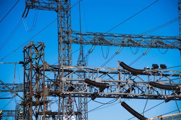 Linhas de transmissão de energia atravessando região montanhosa, ilustrando a expansão da rede elétrica e os desafios logísticos dos leilões de transmissão em áreas remotas.