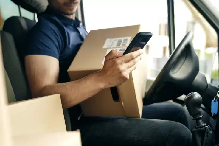Motorista usando celular para atualizar status da entrega.